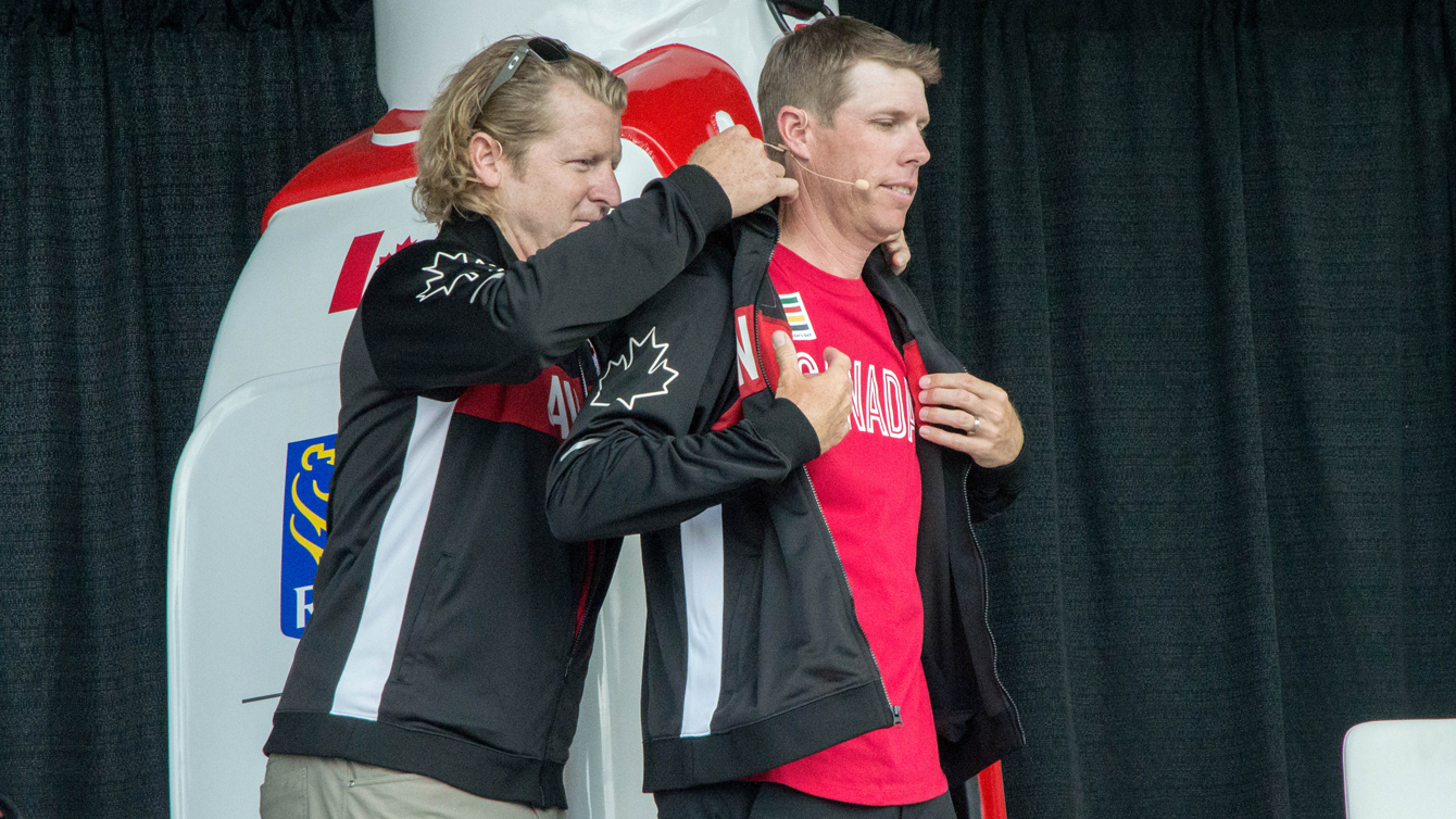 Curt Harnett, Team Canada's chef de mission, gives golfer David Hearn his Olympic jacket at the Glen Abbey Golf Club on July 19, 2016. (Tavia Bakowski/COC)