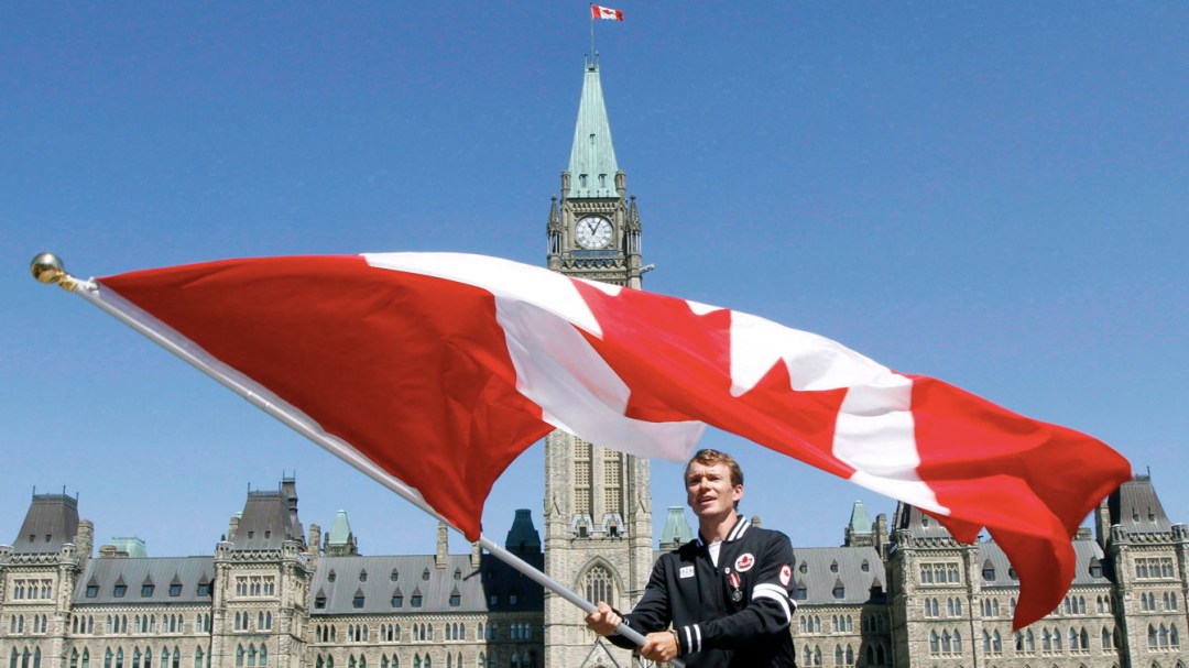 Simon Whitfield with the Canadian flag on Parliament Hill