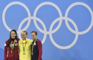 Sweden's gold medal winner Sarah Sjostrom is flanked by Canada's silver medal winner Penny Oleksiakand, left, and United States' bronze medal winner Dana Vollmer during the medal ceremony for the women's 100-meter butterfly final at the swimming competitions at the 2016 Summer Olympics, Sunday, Aug. 7, 2016, in Rio de Janeiro, Brazil. (AP Photo/Martin Meissner)