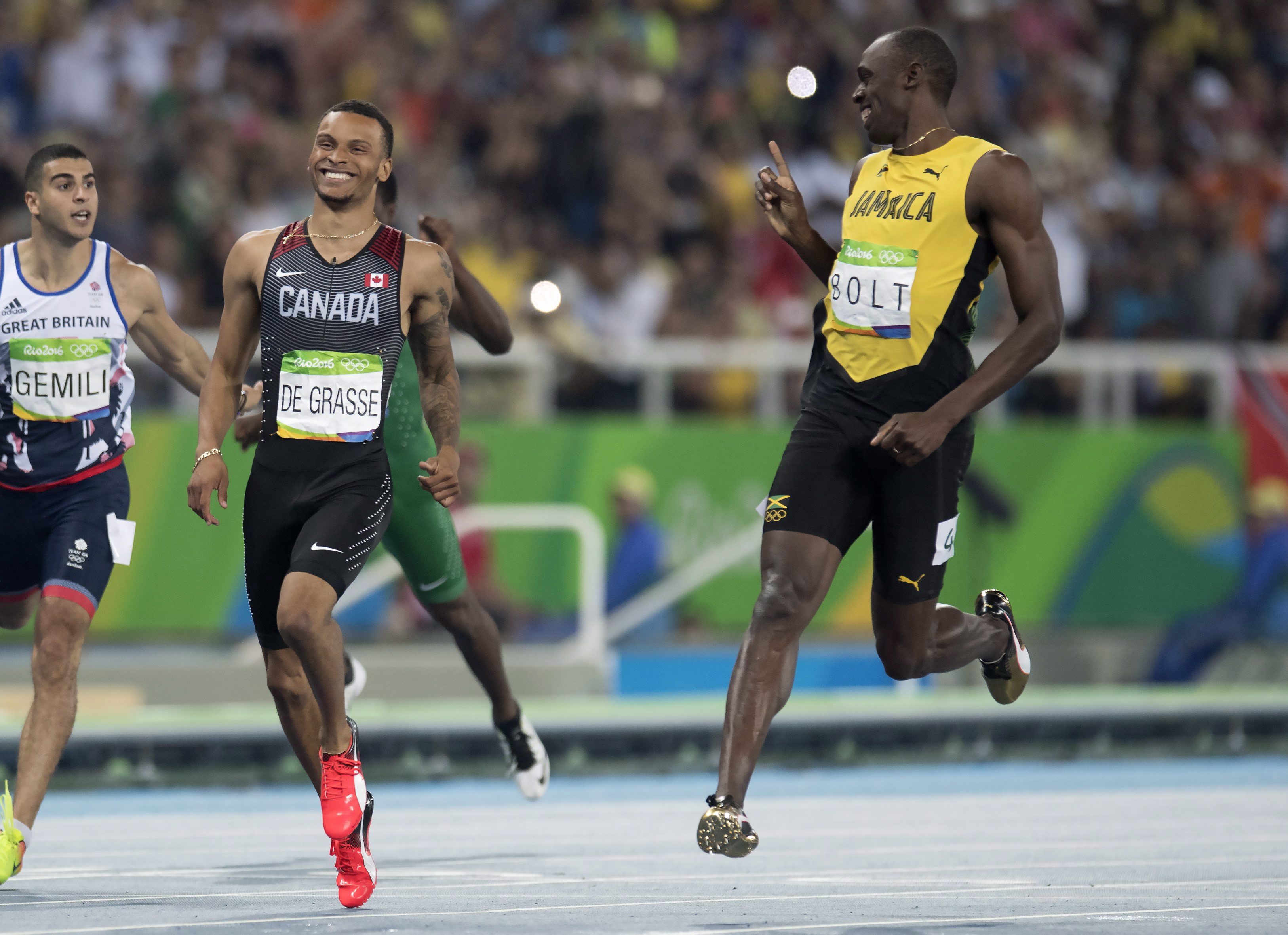Bolt and De Grasse smiling as they cross the finish line 