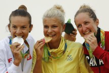 Rio 2016: Catharine Pendral Gold medalist Jenny Rissveds of Sweden, center, silver medalist Maja Wloszczowska of Poland, left, and bronze medalist Catharine Pendrel of Canada, right, bite they medals on the podium of the women's cross-country mountain bike race at the 2016 Summer Olympics in Rio de Janeiro, Brazil, Saturday, Aug. 20, 2016. (AP Photo/Patrick Semansky)