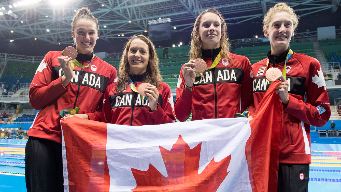 (L-R), Chantal Van Landeghem, Sandrine Mainville, Penny Oleksiak and Taylor Ruck celebrate their Olympic bronze medal in women's 4x100m freestyle relay on August 6, 2016. 