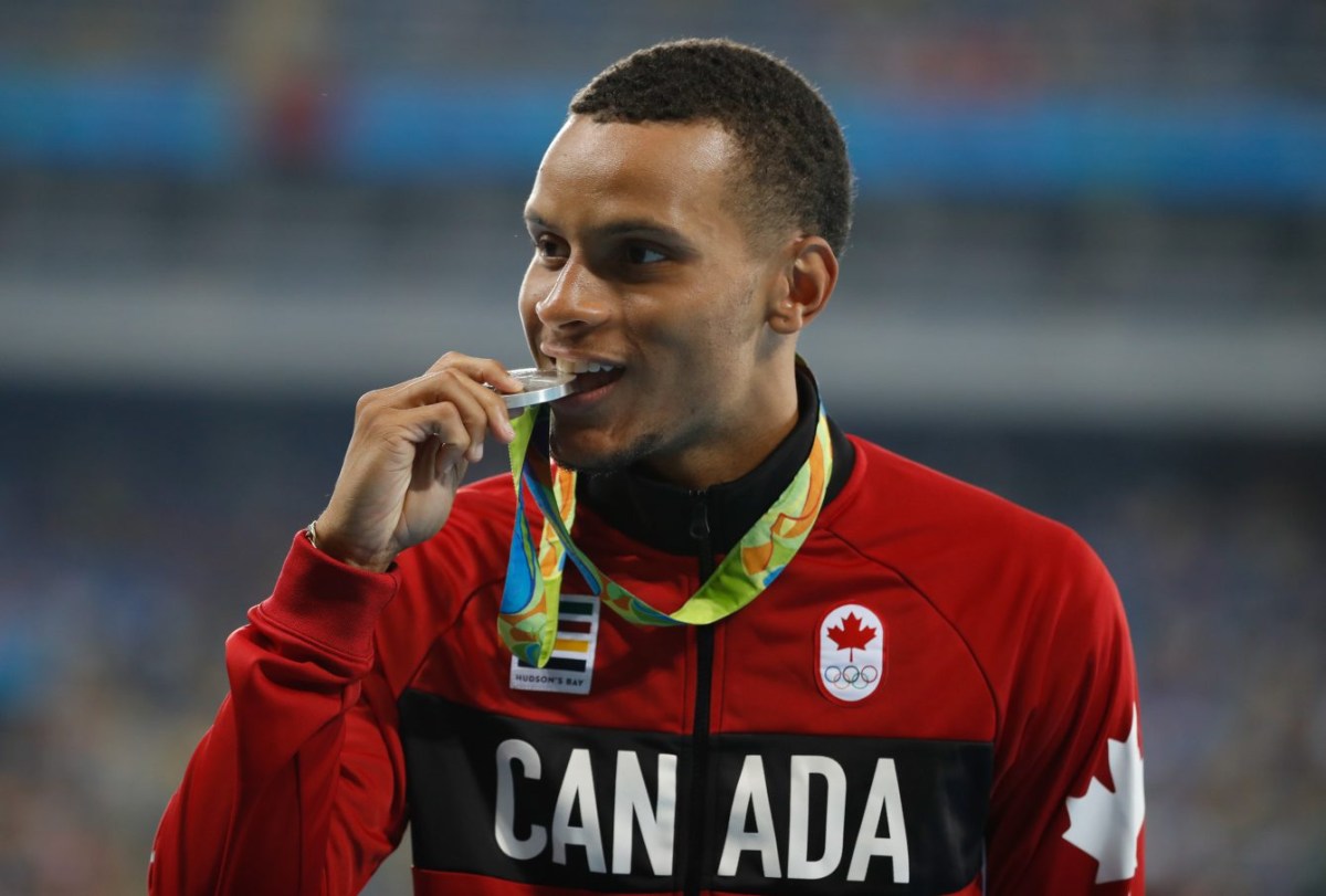 Andre De Grase bites his silver medal on the podium