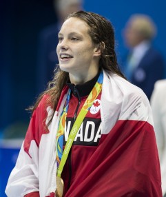 Canada's Penny Oleksiak with her flag and gold medal after finishing first in the women's 100-meter freestyle during the swimming competitions at the 2016 Summer Olympics, Thursday, Aug. 11, 2016, in Rio de Janeiro, Brazil. (COC photo/Stephen Hosier)