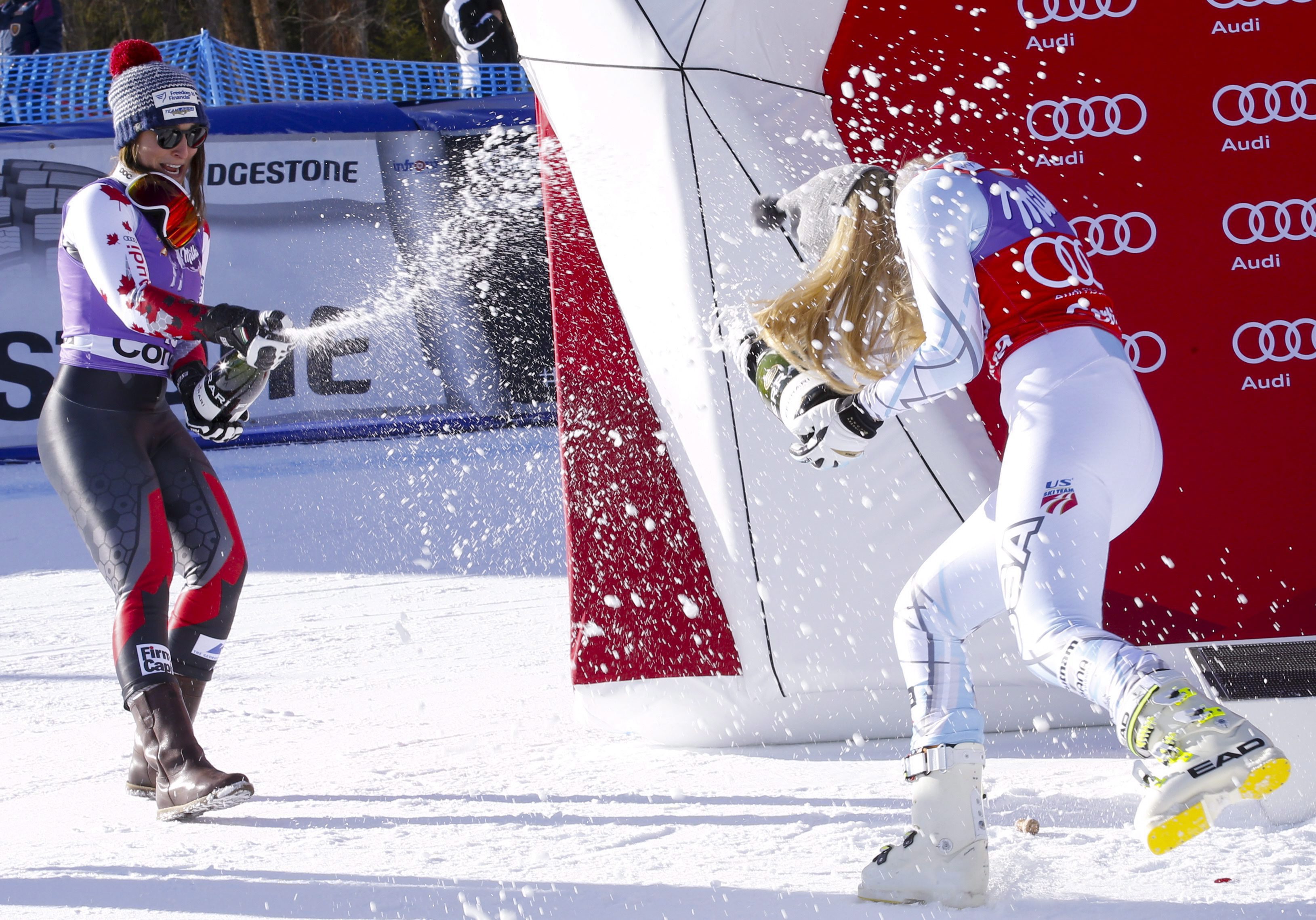 Lindsey Vonn, of the United States, right, sprays sparkling wine with second placed Canada's Larisa Yurkiw, after winning an alpine ski, women's World Cup downhill, in Cortina D'Ampezzo, Italy, Saturday, Jan. 23, 2016. (AP Photo/Armando Trovati)