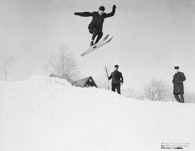Ski jumping in the 1900s. Black and white image of a male athlete jumping over a hill.