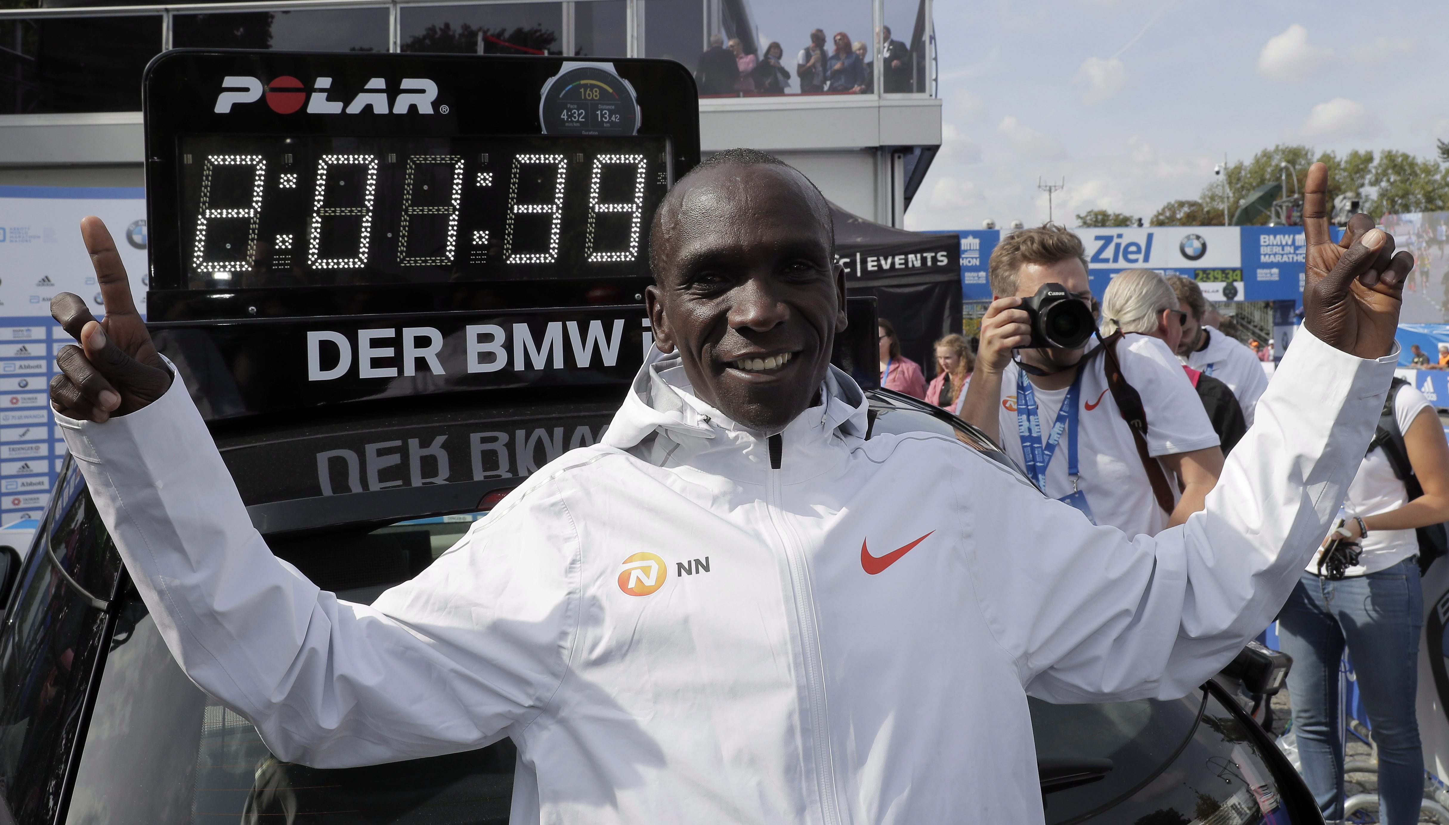 Eliud Kipchoge in front of the clock showing his world record time