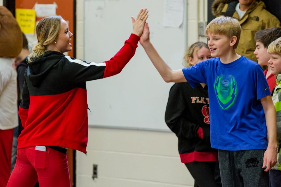 Sarah Wells high-fiving student at a school