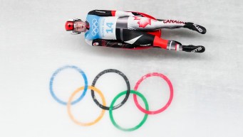Reid Watts slides past the Olympic rings on a luge track