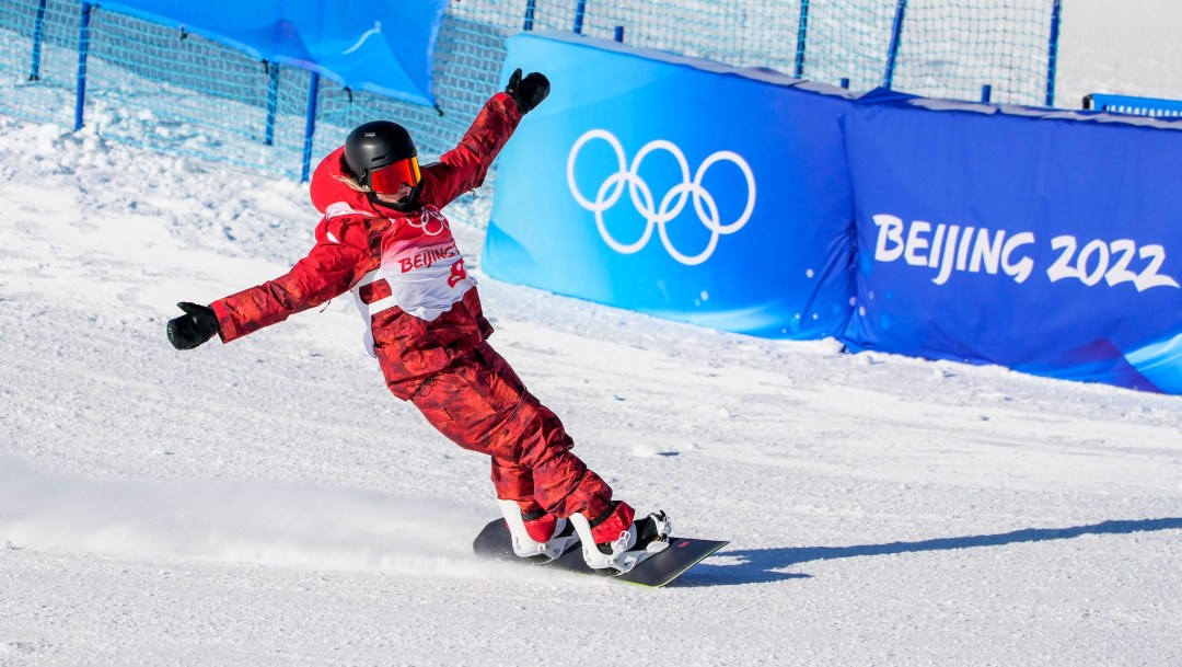 Laurie Blouin raises her arms as she glides into the finish area on her snowboard