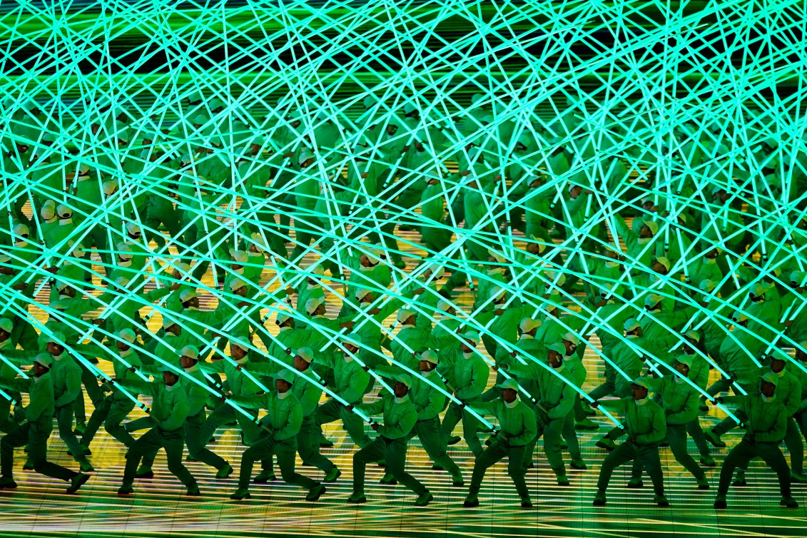 Dancers with long green illuminated poles 