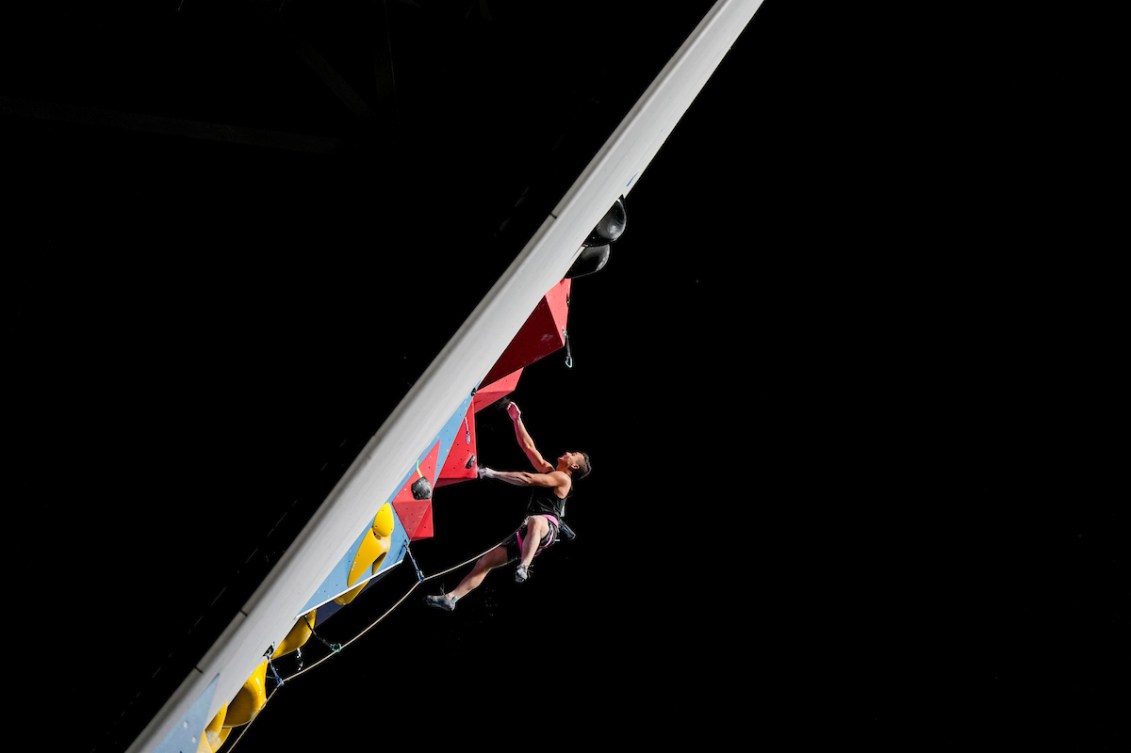 Sean McColl navigates a lead climbing wall against a black night sky 