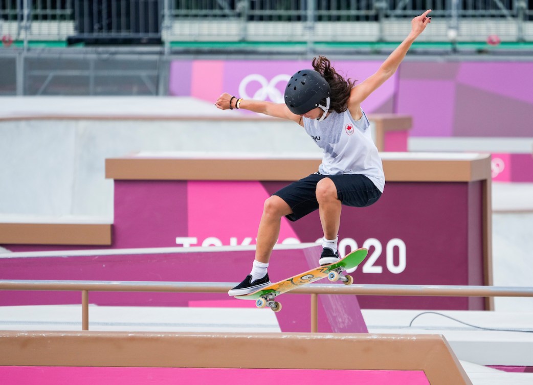 Annie Guglia rides her skateboard along a rail in competition