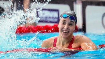 Mary Sophie Harvey smiles as she hangs onto a red lane rope in the swimming pool