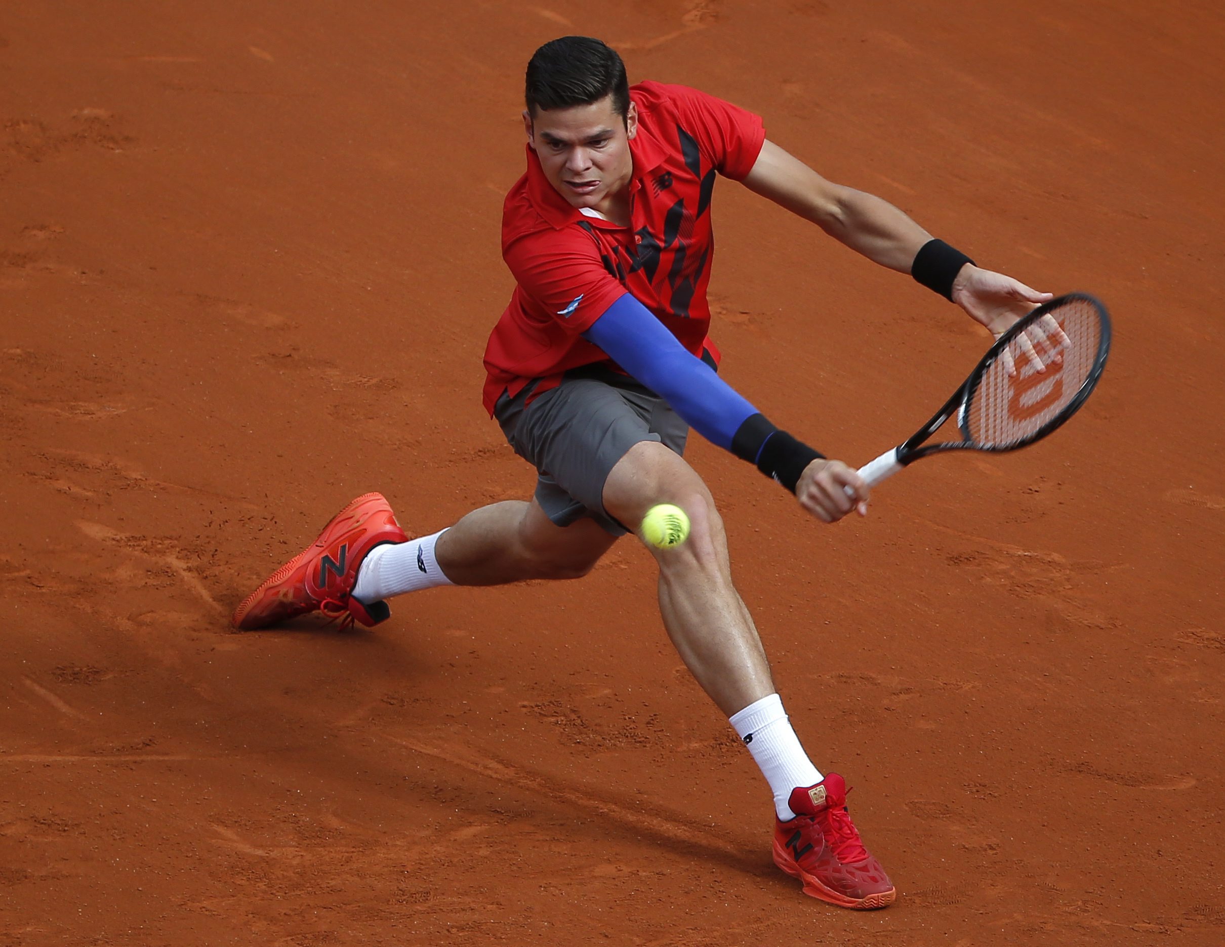 Milos Raonic backhands the ball