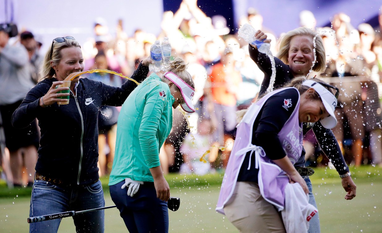 Brooke Henderson and her caddy sister are doused with water and sports drinks after a win 