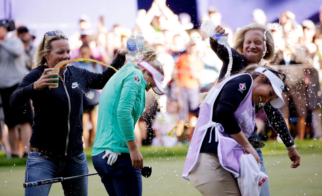 Brooke Henderson and her caddy sister are doused with water and sports drinks after a win