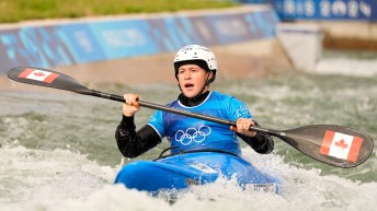 Lois Betteridge competes in canoe cross while wearing a blue jersey