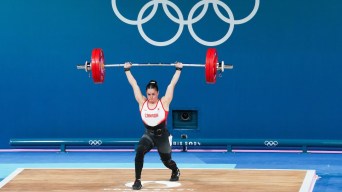 Maude Charron lifts a barbell over her head