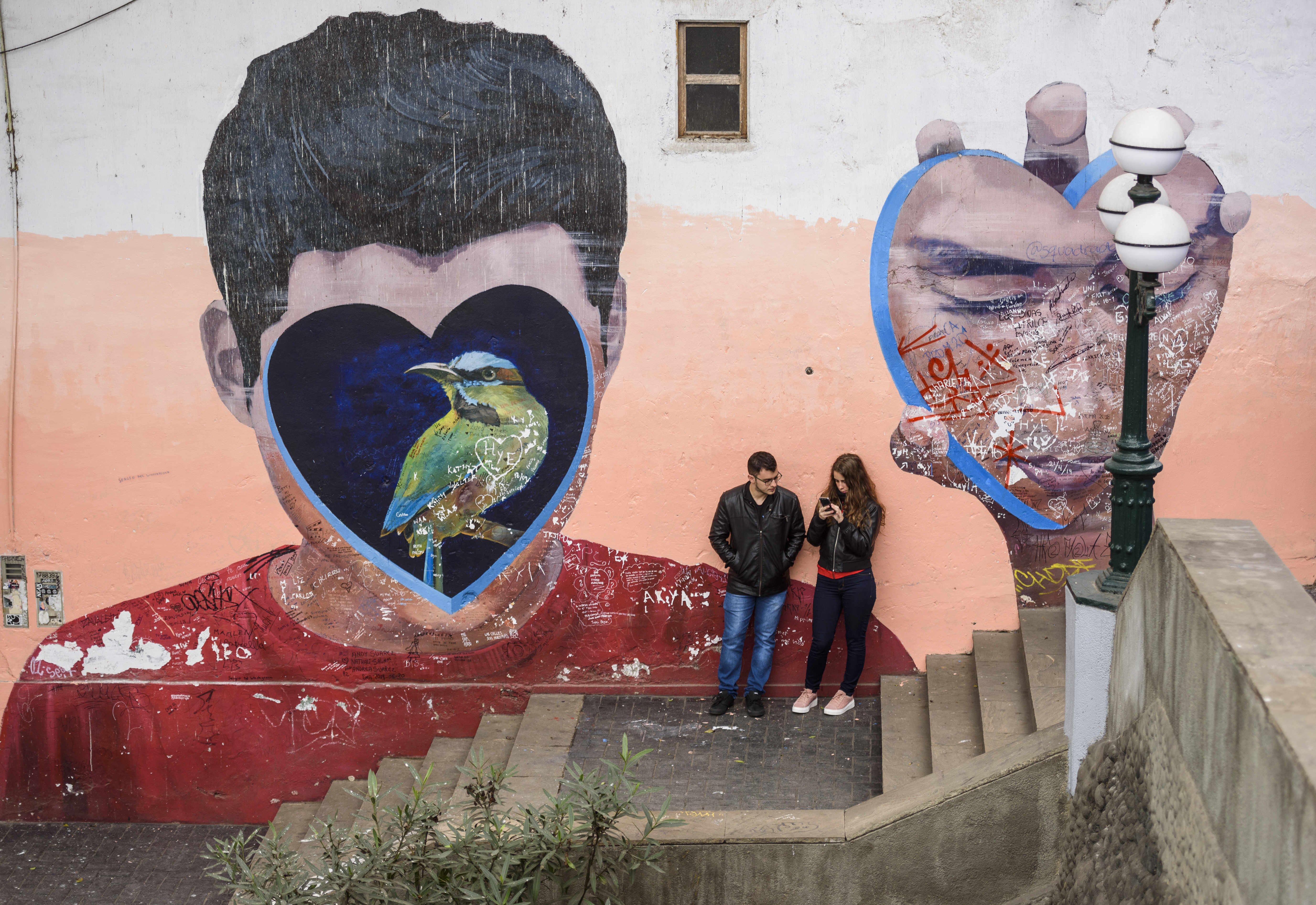 Street art of a person with a heart and bird covering his face