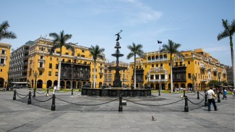 Yellow buildings behind a statue and palm trees in Lima