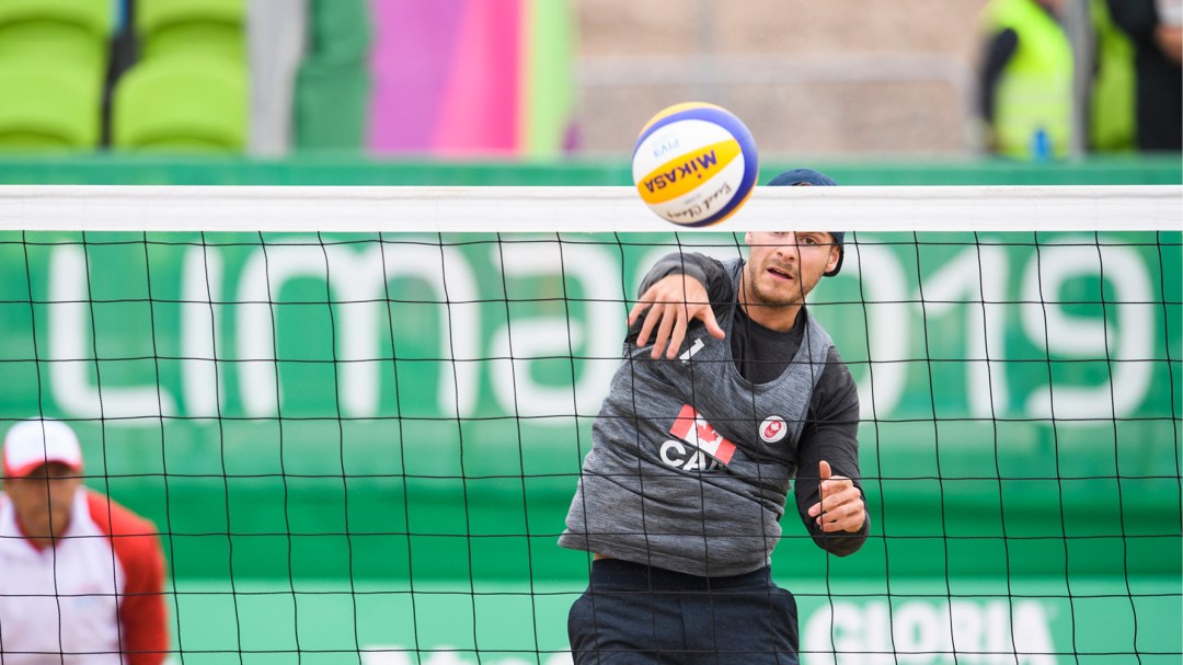 Volleyball player spikes ball over net