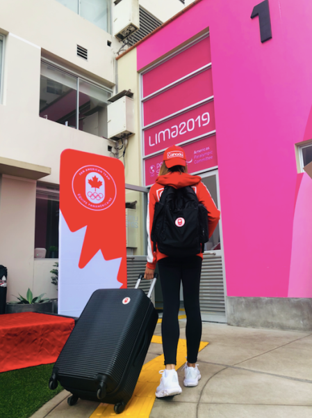 Athlete showing off her new jacket, suitcase, backpack and hat.