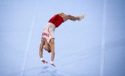 Male gymnast does a back handspring on the floor.