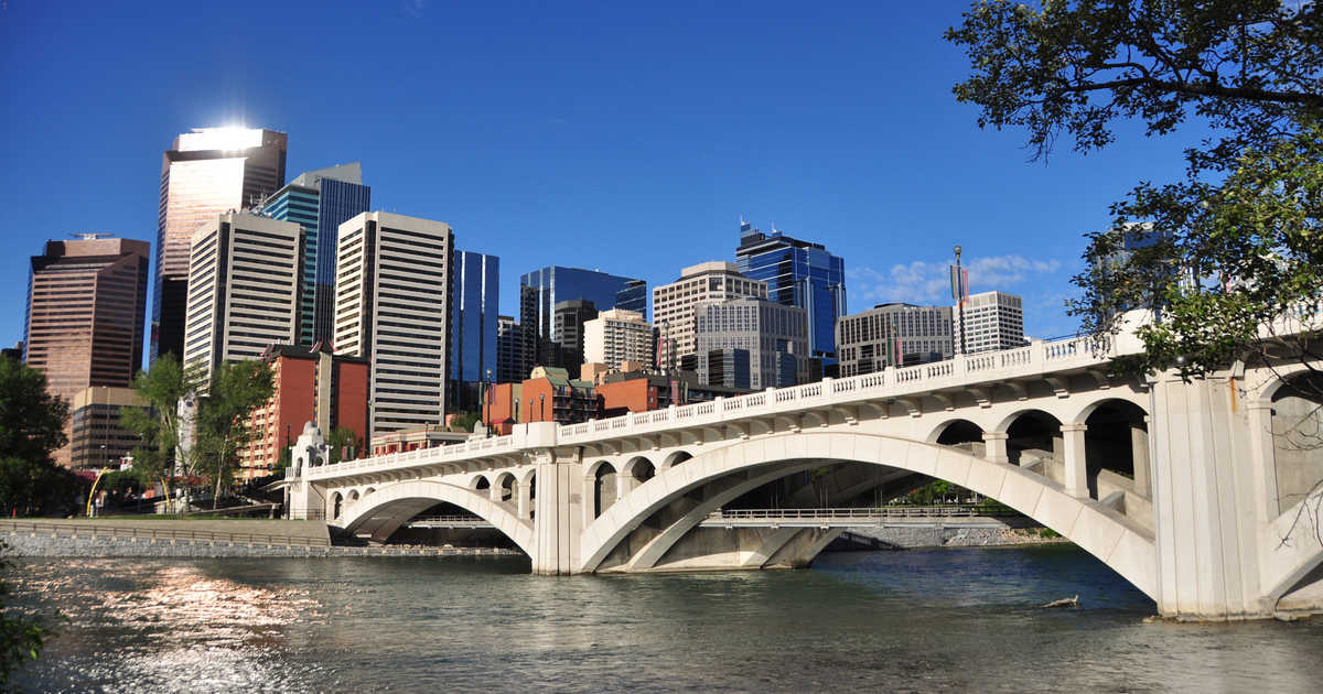 Bridge going across a river with the city landscape in the back.