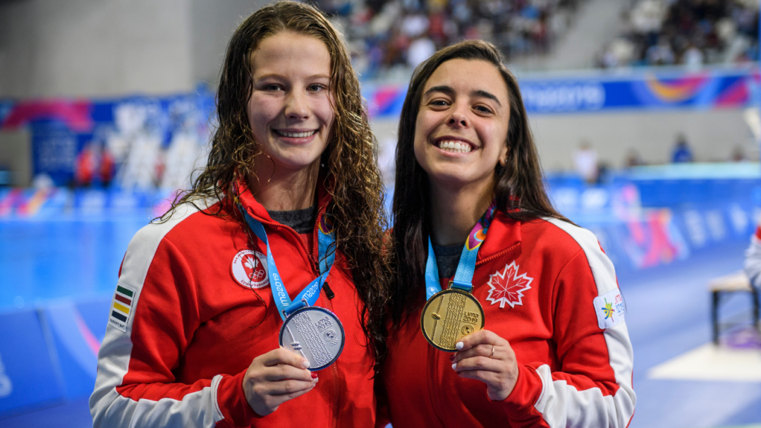 Two athletes pose with medals