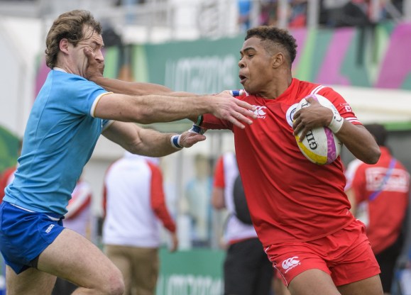 rugby player blocks a tackle from player on another team