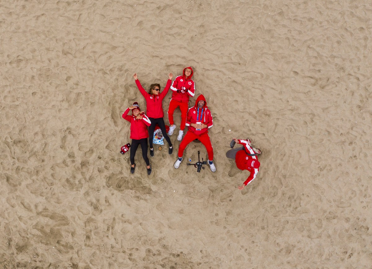 Surfers in their Team Canada Kits lay on the sand