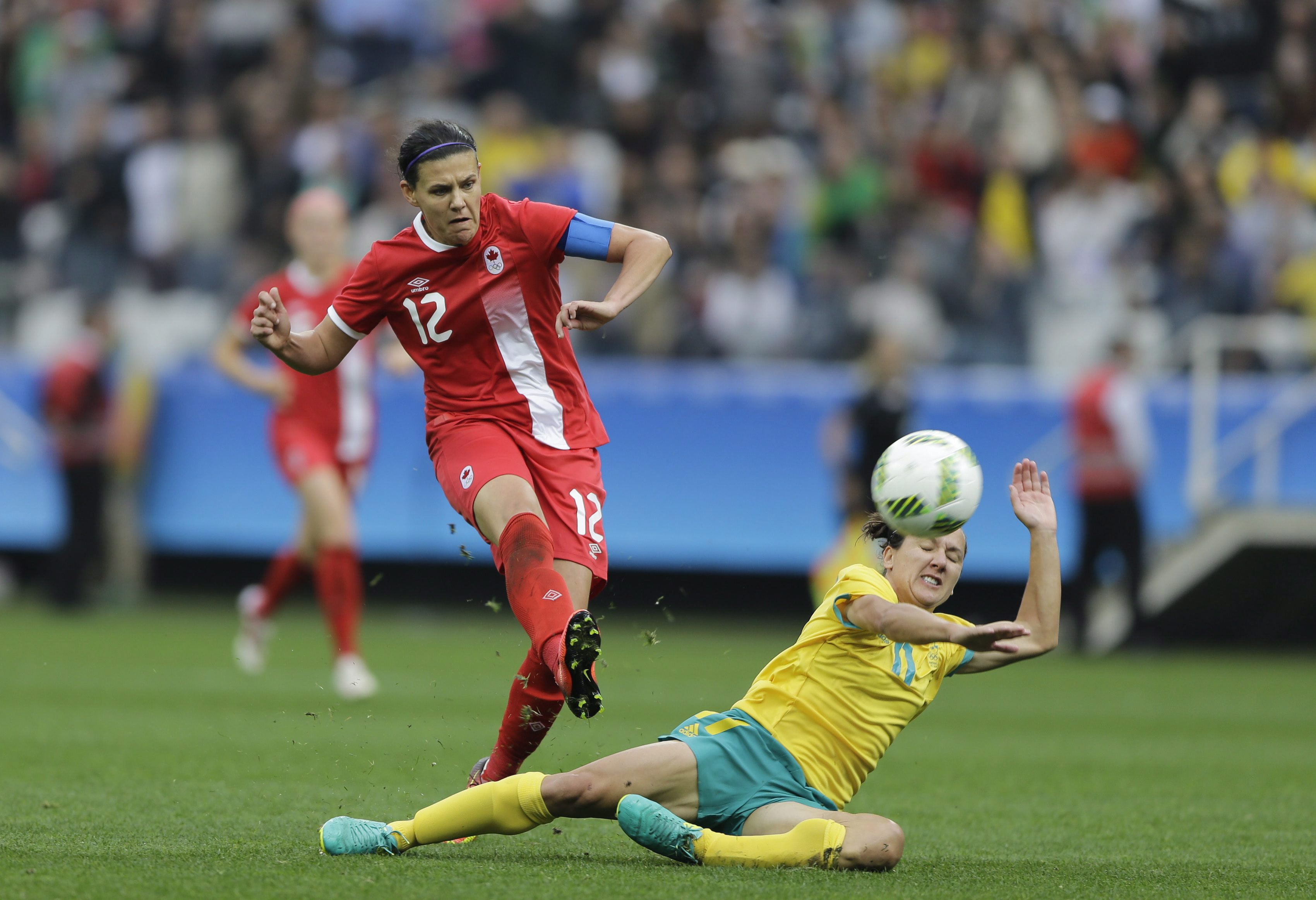 Christine Sinclair kicks the ball over a fallen Team Australian player. 