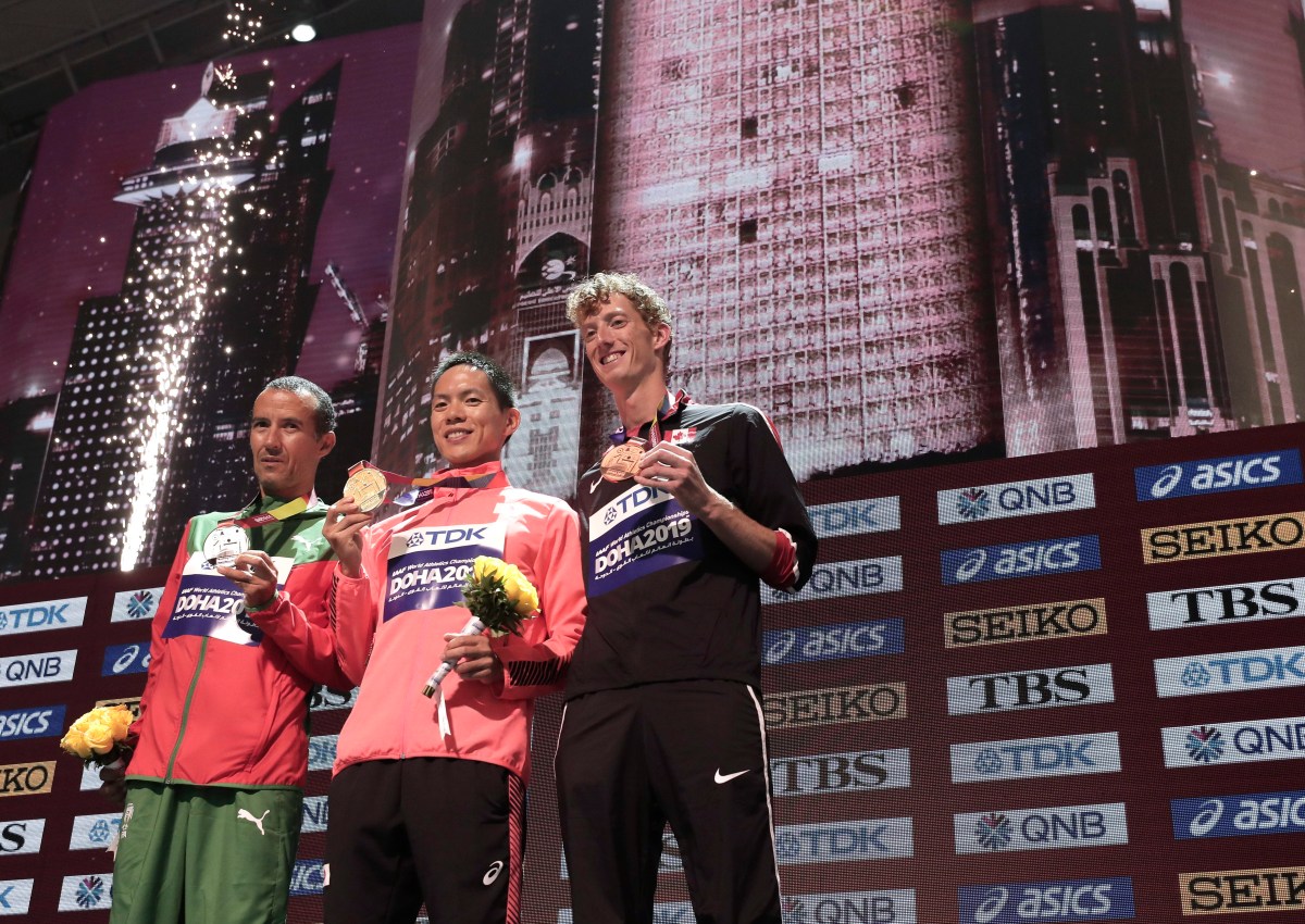 Evan Dunfee stands on the podium with his bronze medal alongside the first and second place winner.