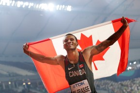Andre de Grasse holds the Canadian flag over his head as he celebrates his silver medal in Doha.