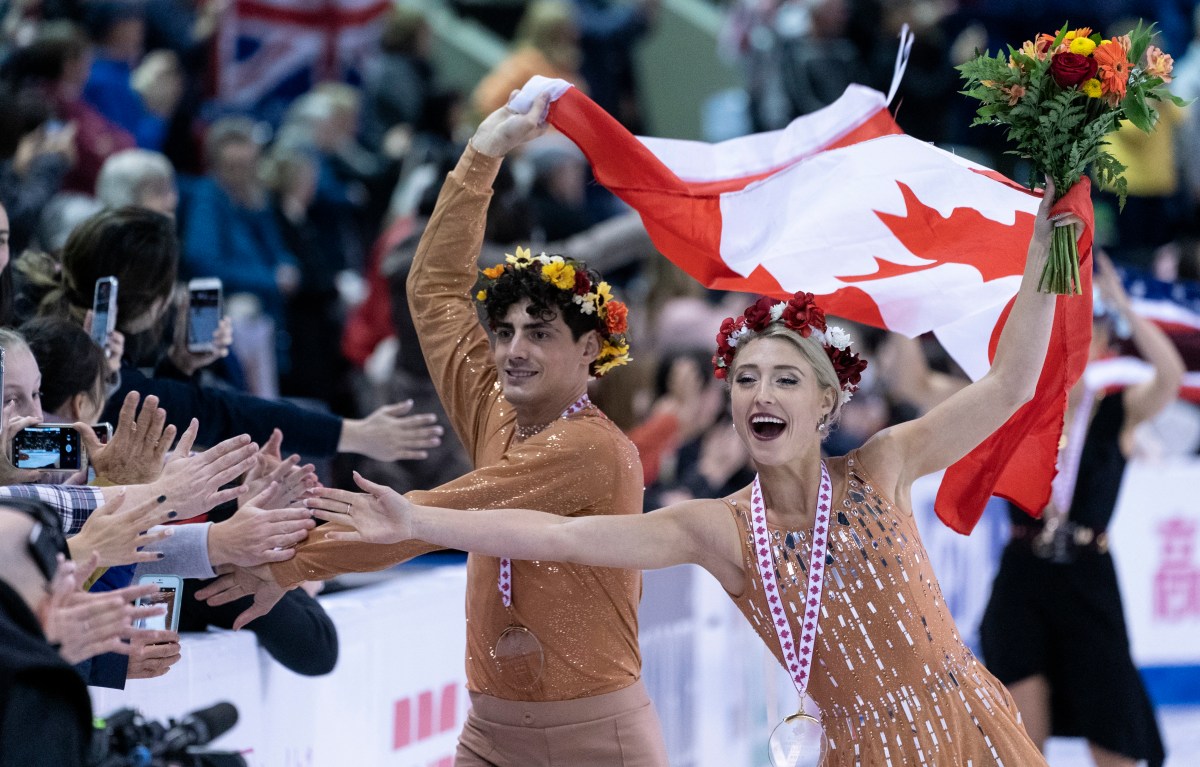 Piper Gilles and Paul Poirier reach out to the crowd during victory ceremonies at Skate Canada