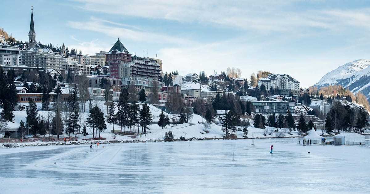 Winter in Lake St. Moritz in Switzerland, with the lake frozen and buildings surrounding it.