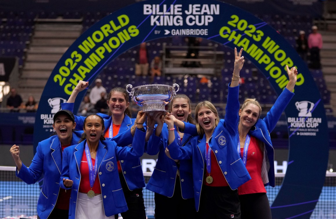 Canada's tennis team hold up the Billie Jean King Cup trophy while wearing blue blazers