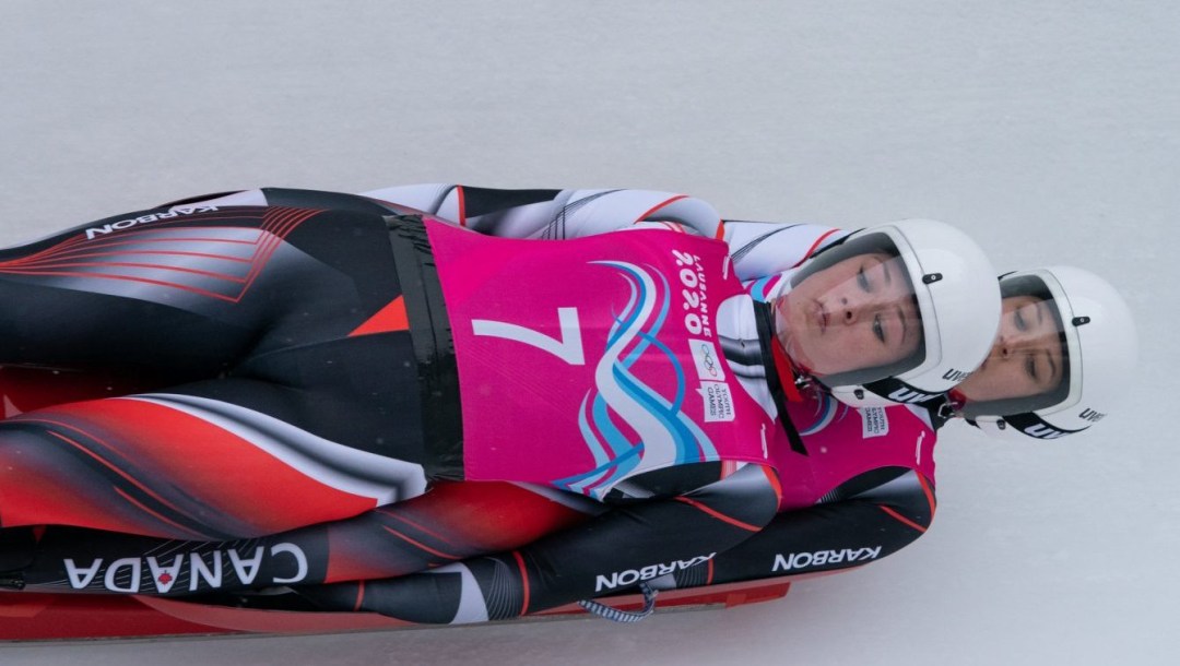A women's doubles luge team slides down the track