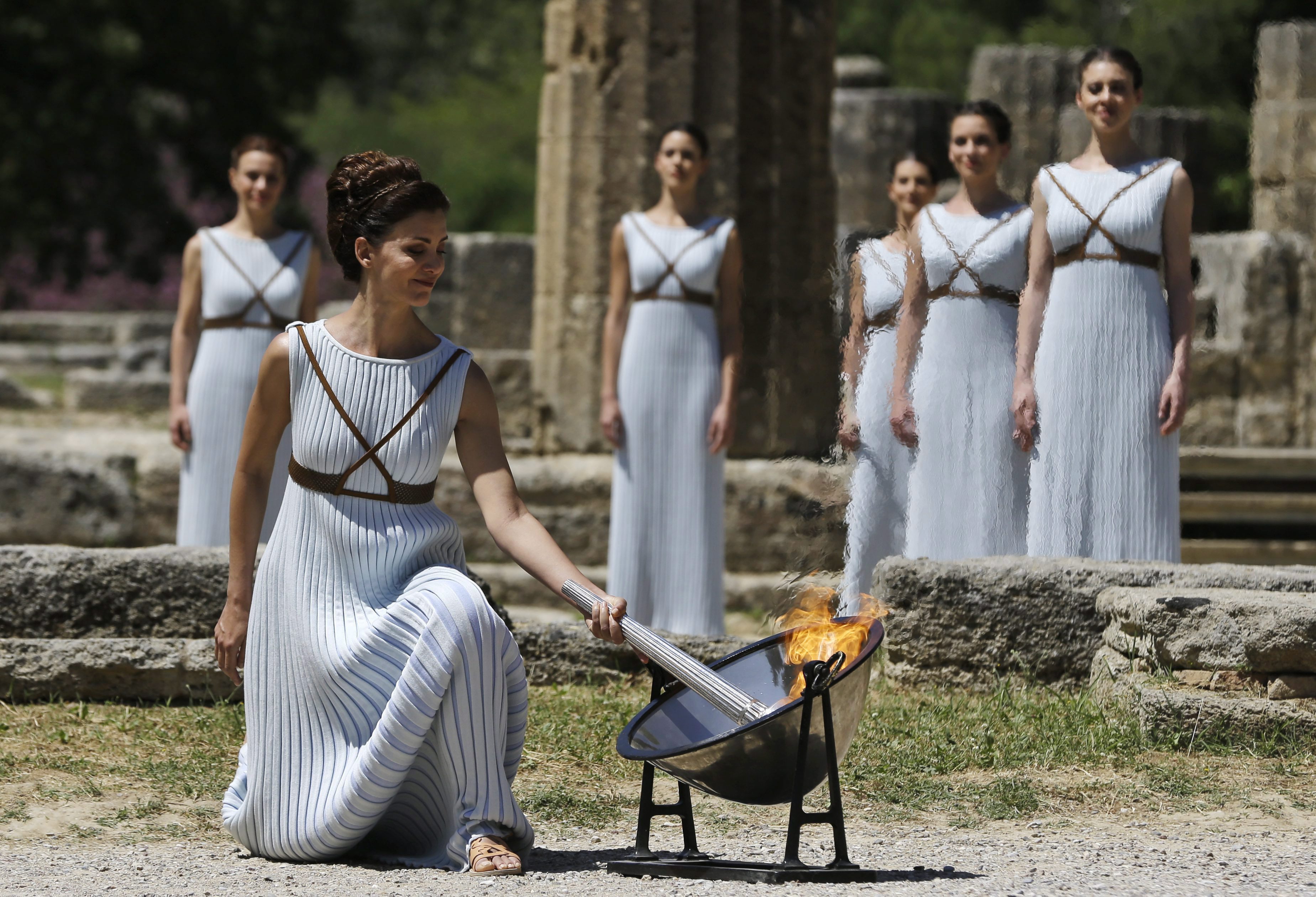 A dancer dressed as priestesses lights the Rio Olympic torch with a parabolic mirror
