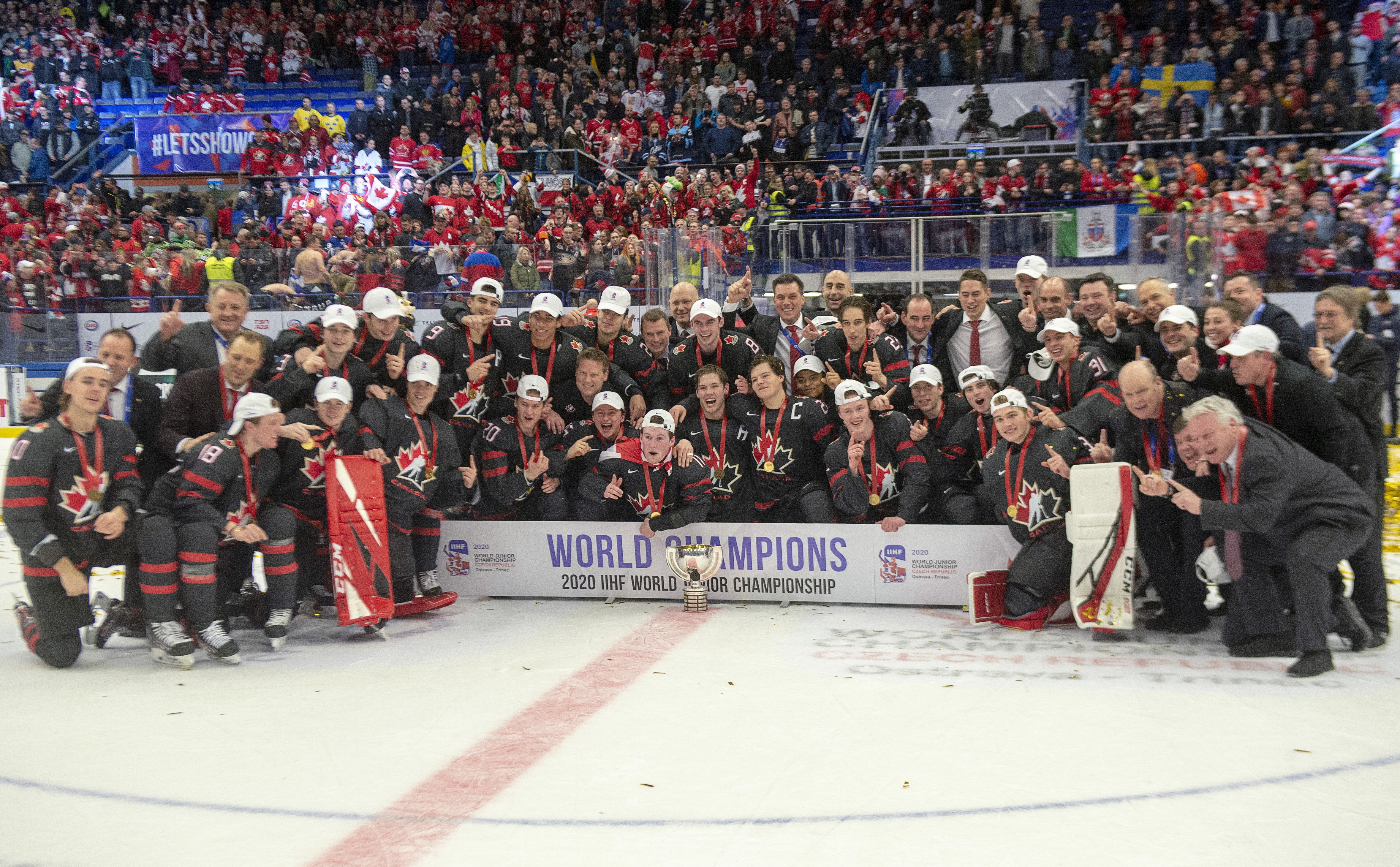 Un groupe de joueurs de hockey pose sur la glace avec la bannière des champions.
