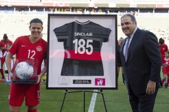 Christine Sinclair is given a commemorative jersey by Victor Montagliani.