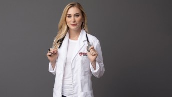 Joannie Rochette holds a stethoscope over her shoulders, posing for a photo in her white doctor's coat.