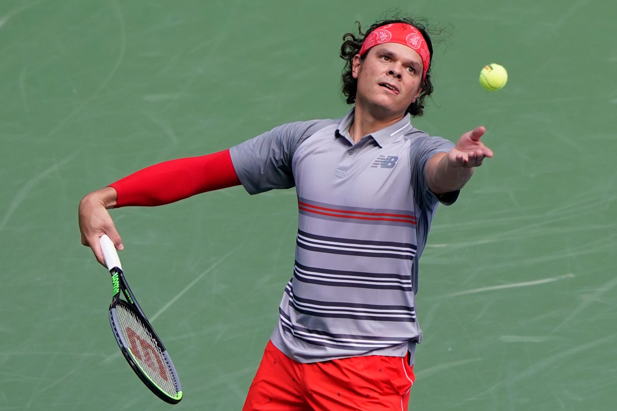 Milos throws the ball in the air to serve it.