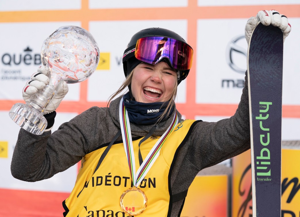 Elena Gaskell holds up the Crystal Globe in her right hand with a big smile while holding onto the top of her skis which are vertical.