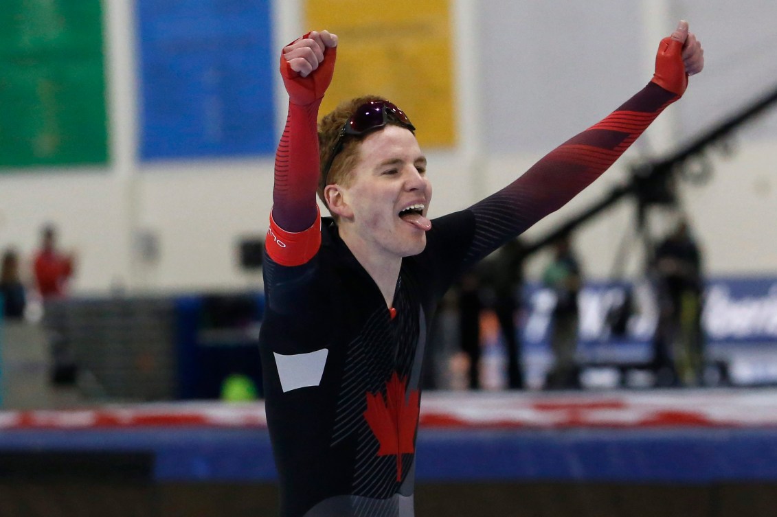 Graeme fish lève les bras dans les airs pour célébrer sa victoire en patinage de vitesse longue piste.