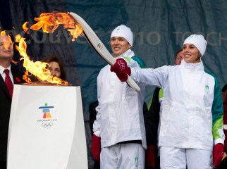 Two torchbearers light their torch from a cauldron