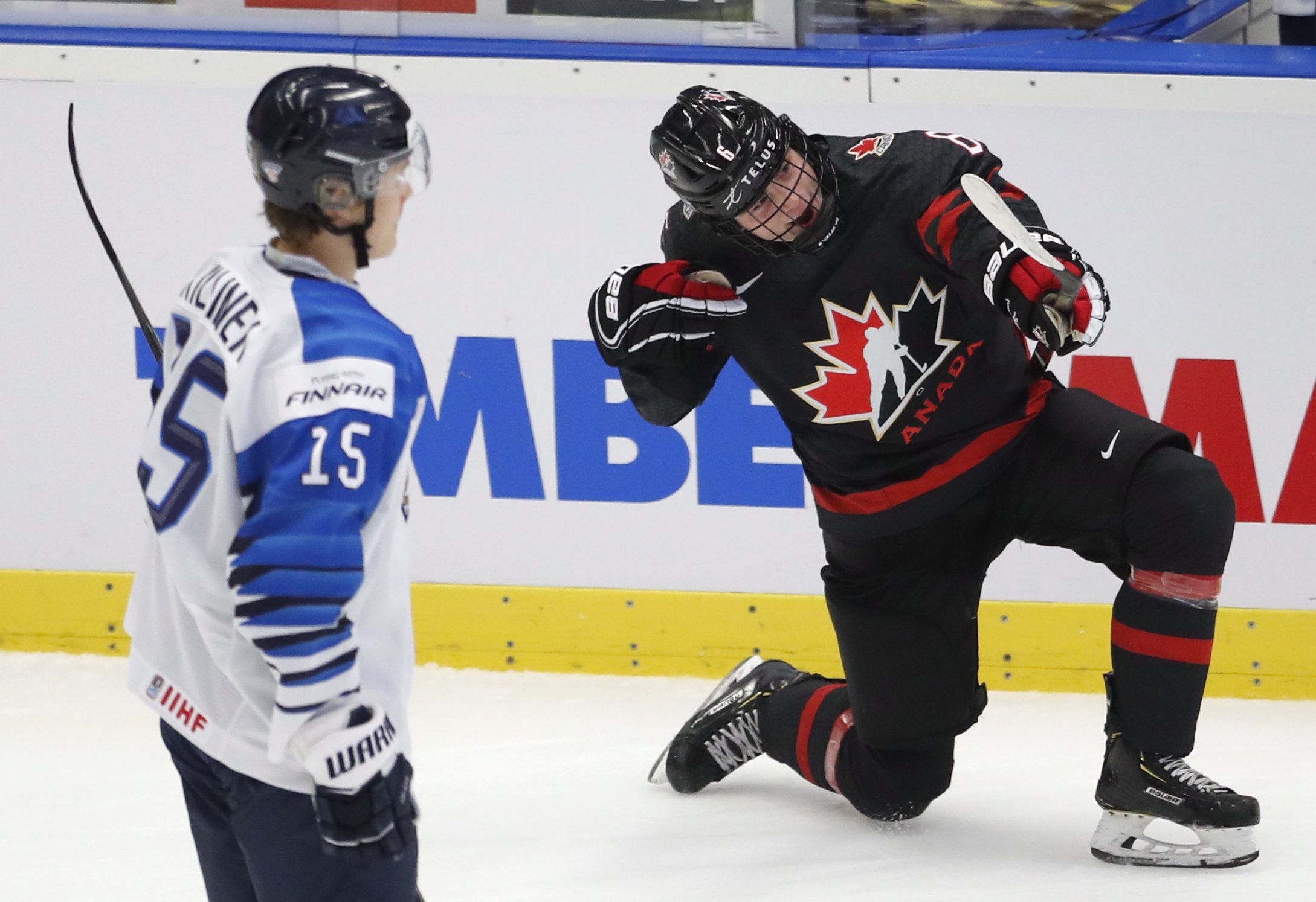 Un joueur du Canada célèbre un but devant un joueur de la Finlande.
