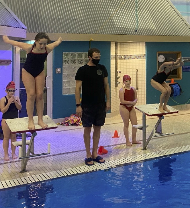 Coach with swimmers on start blocks