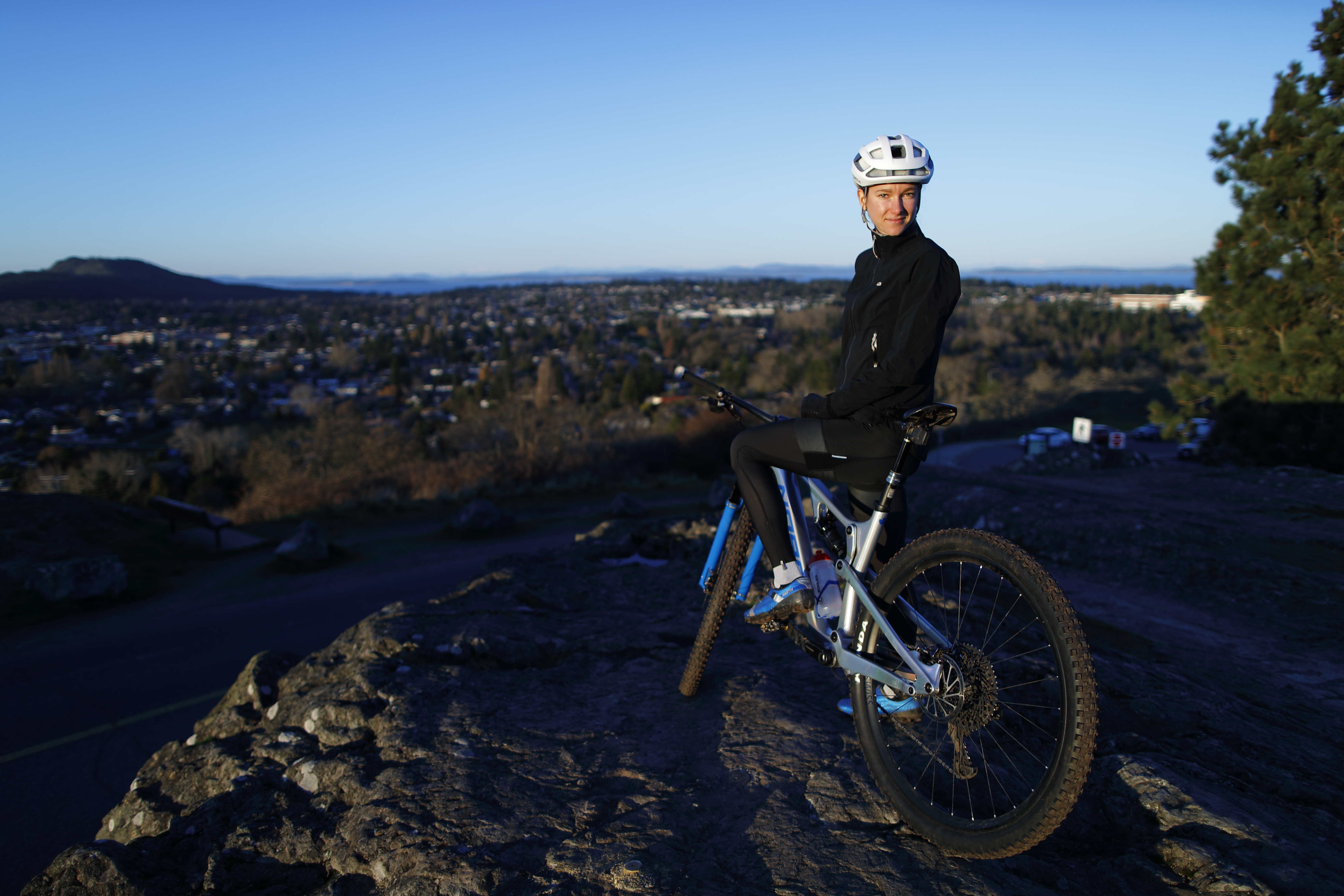 Haley Smith on her mountain bike looking over the city from a hill 
